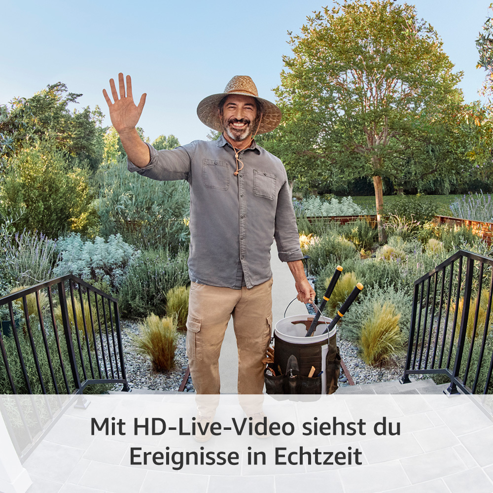 Mann mit Strohhut winkt. Hält Eimer mit Werkzeugen. Steht auf Stufen mit Geländer, umgeben von Grün in sonniger Umgebung.
