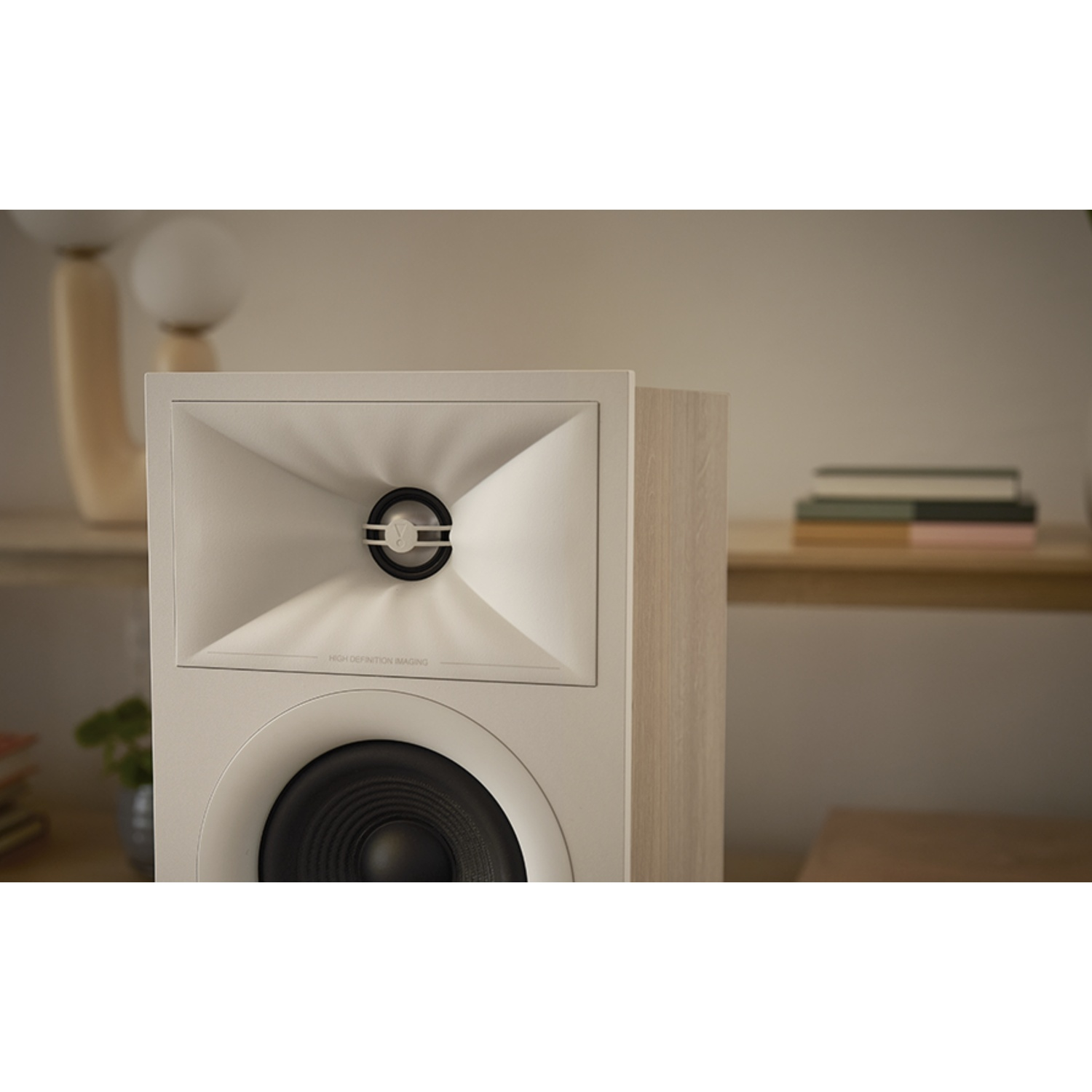 Un altoparlante bianco con cono nero, posto su una mensola di legno. Lo sfondo presenta altri elementi decorativi.