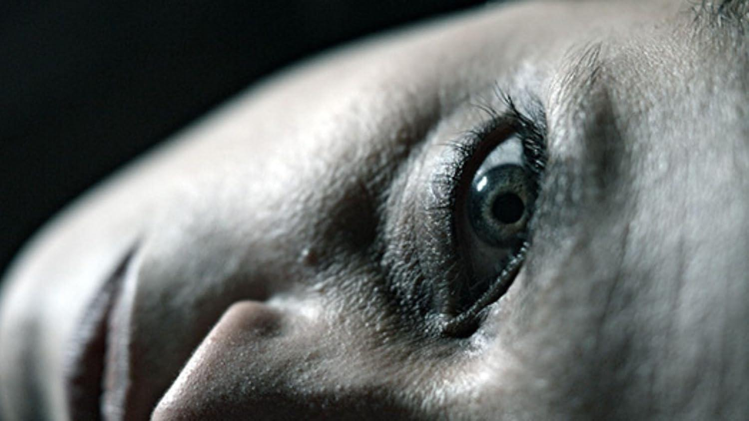 Nahaufnahme eines Auges, das nach oben blickt. Das Auge ist geöffnet, mit dunkler Pupille und Wimpern. Hautstruktur ist sichtbar.
