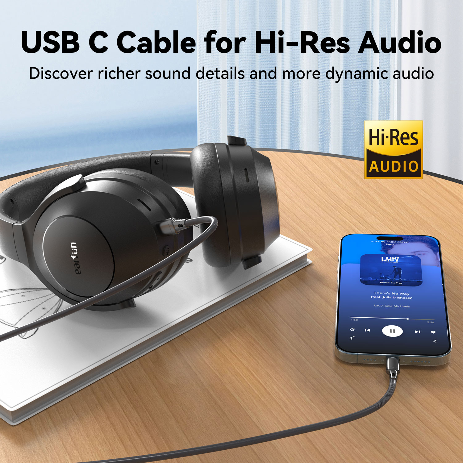 Fekete fejhallgató USB-C kábellel, amely egy zenét játszó telefonhoz csatlakozik. Az audio logó és a szöveg is látható.