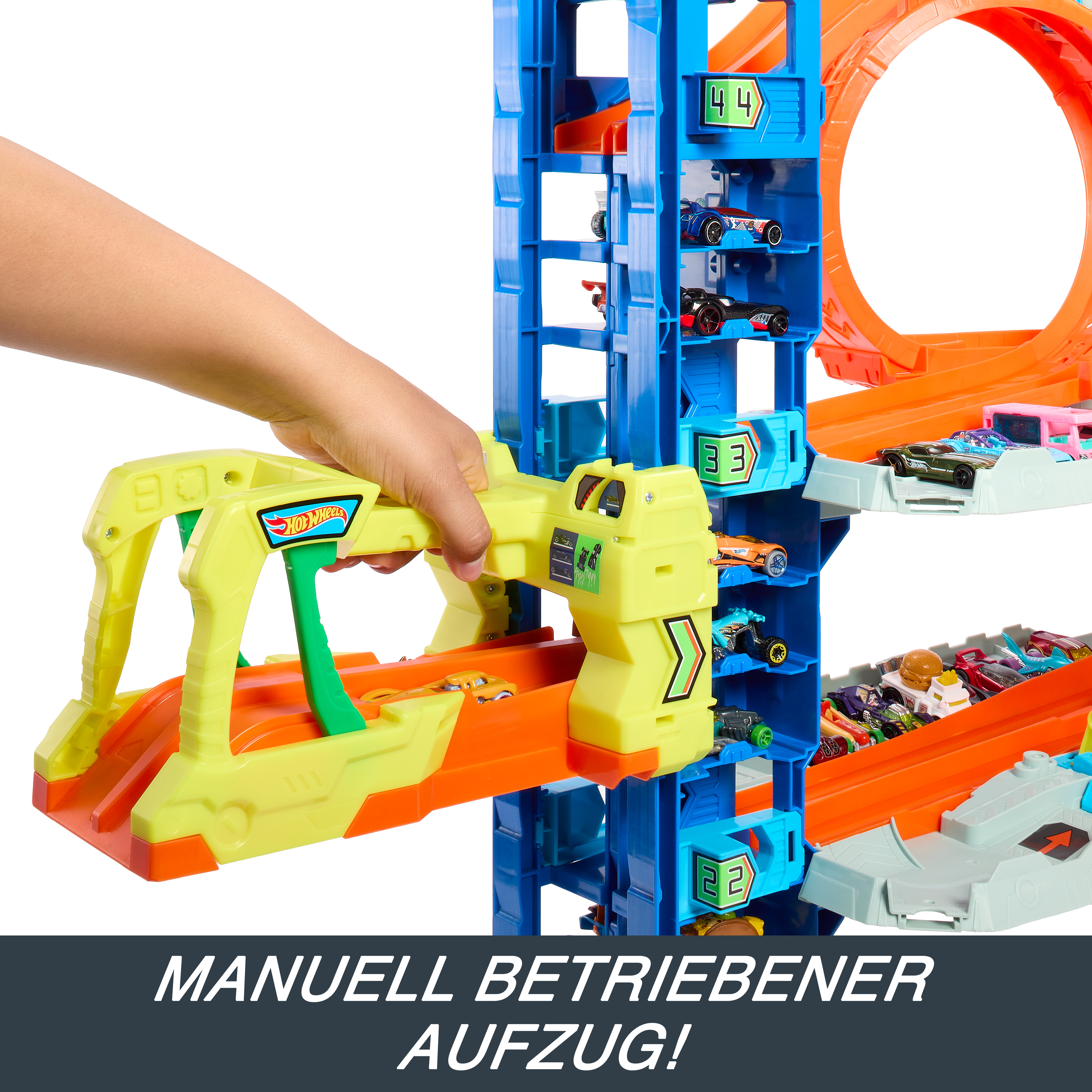 Eine Hand hält einen Hot Wheels-Werfer. Autos sind auf der Strecke, die blau, orange und gelb ist.