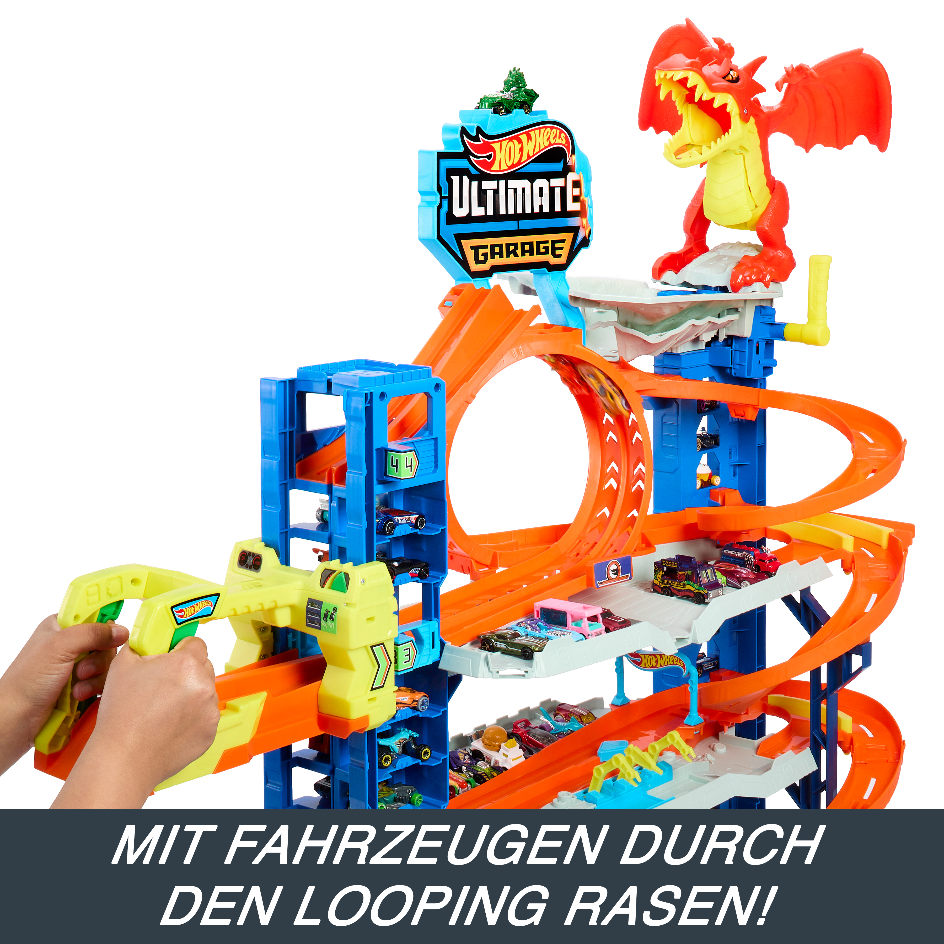 Hot Wheels Ultimate Garage Spielset mit Autos. Enthält eine Schleife, einen Drachen und einen gelben Startmechanismus. Kinderhände sichtbar.