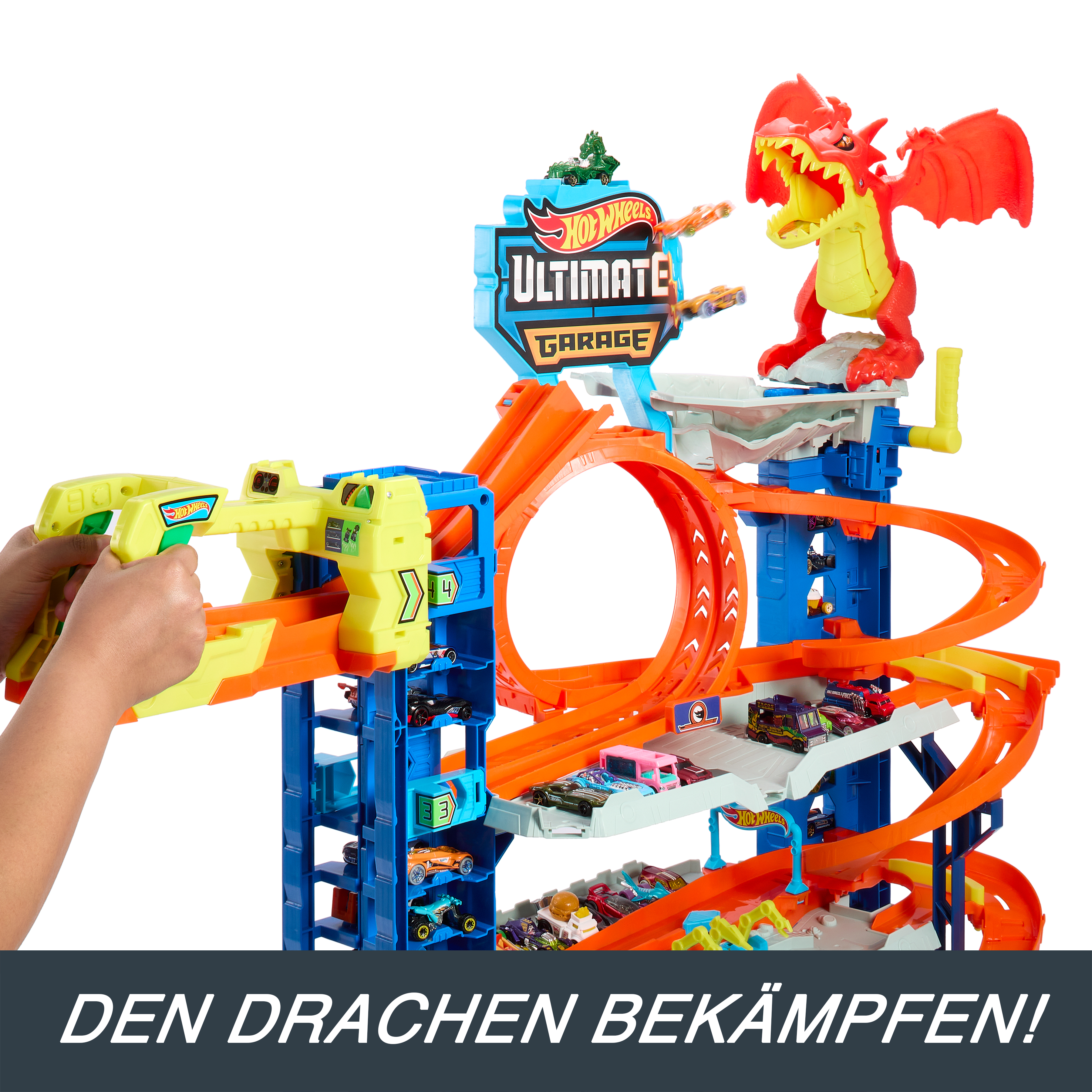 Ein Hot Wheels Ultimate Garage Spielset mit einem Drachen, orangefarbenen Strecken und mehreren Autos. Eine Kinderhand bedient einen gelben Werfer.