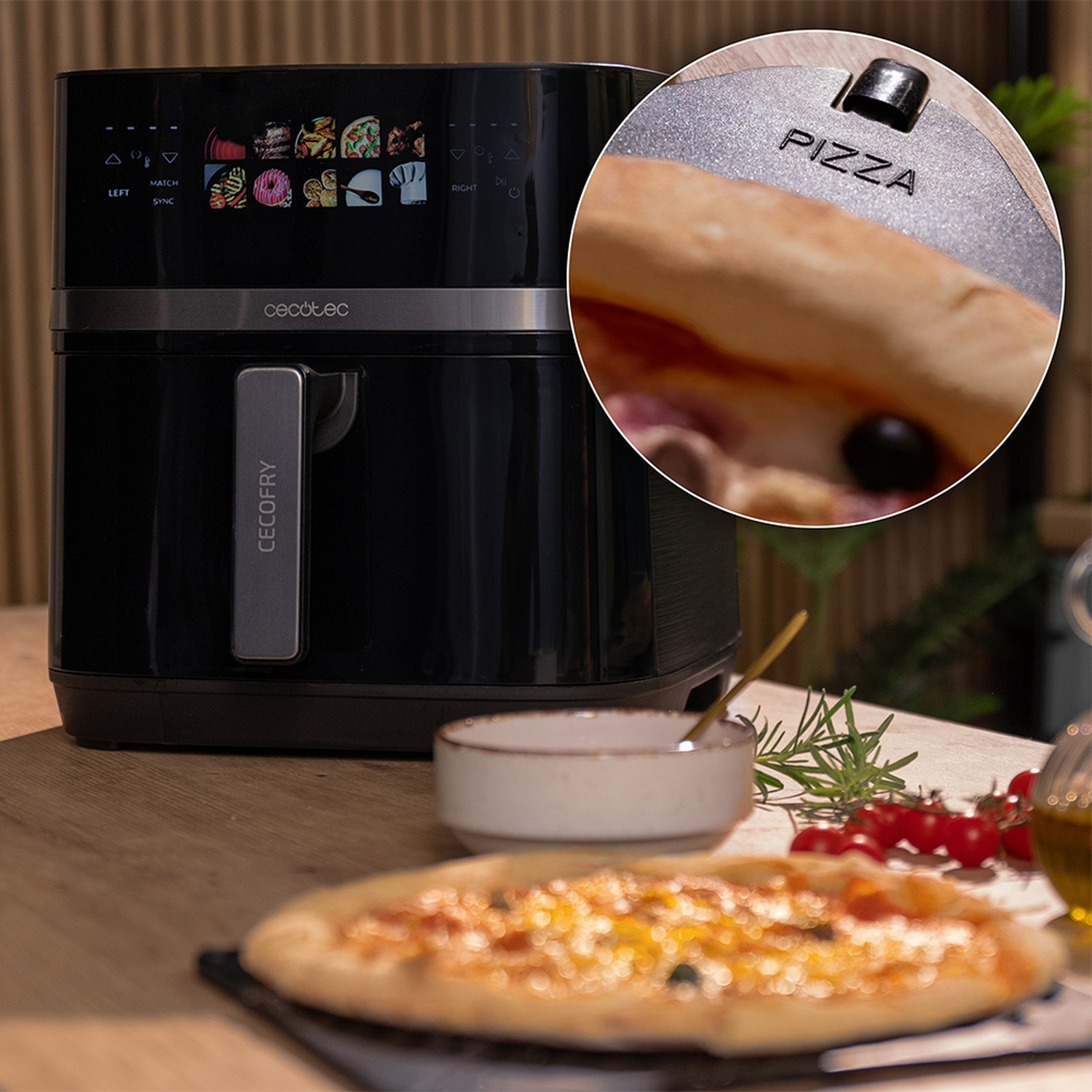 Friggitrice ad aria nera con una pizza a fuoco, anche una pizza su un tavolo con pomodori. Una piccola ciotola è accanto alla friggitrice.