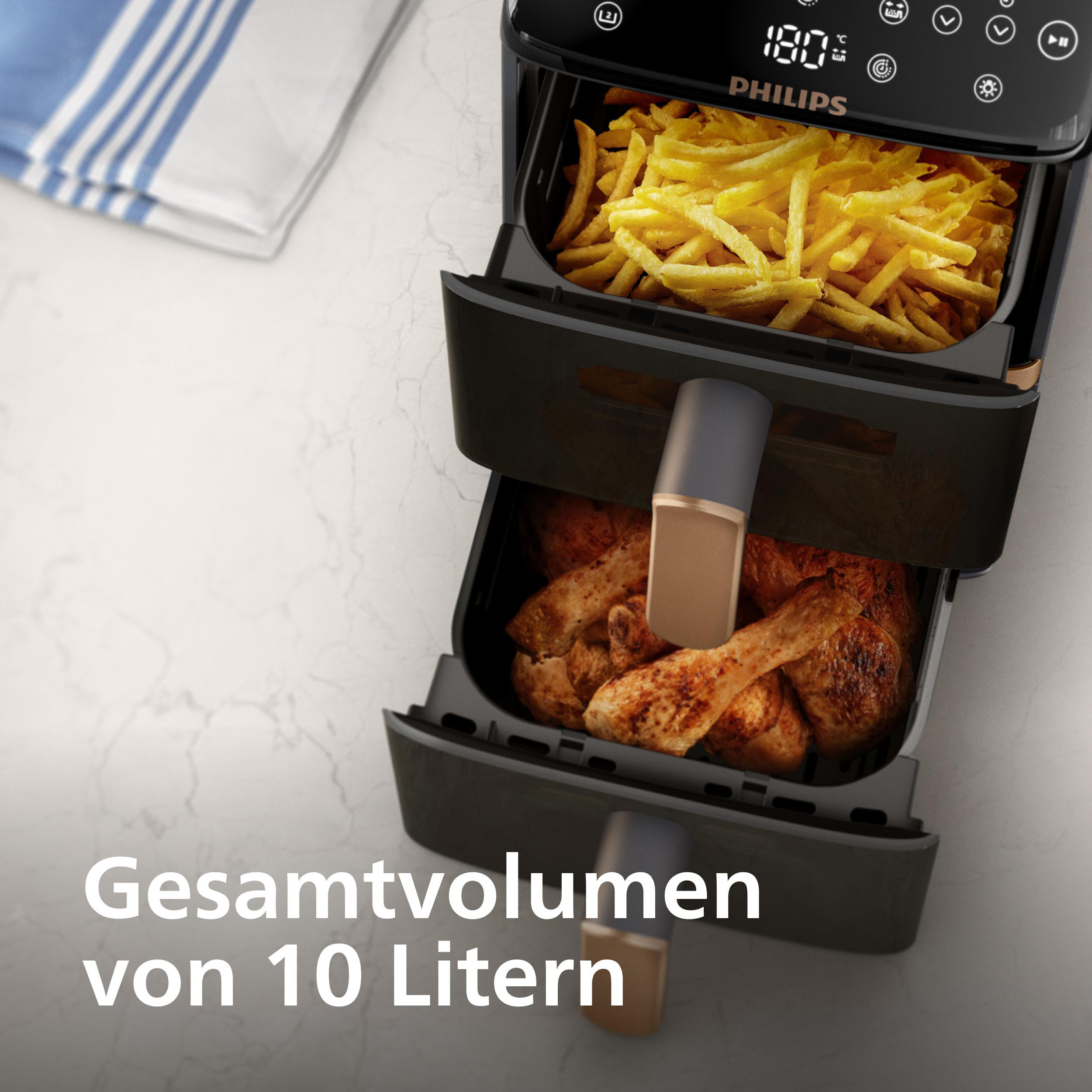 Eine Heißluftfritteuse mit Pommes und Hähnchen. Sie hat eine schwarze Oberfläche, Marke Philips. Gesamtvolumen 10 Liter.