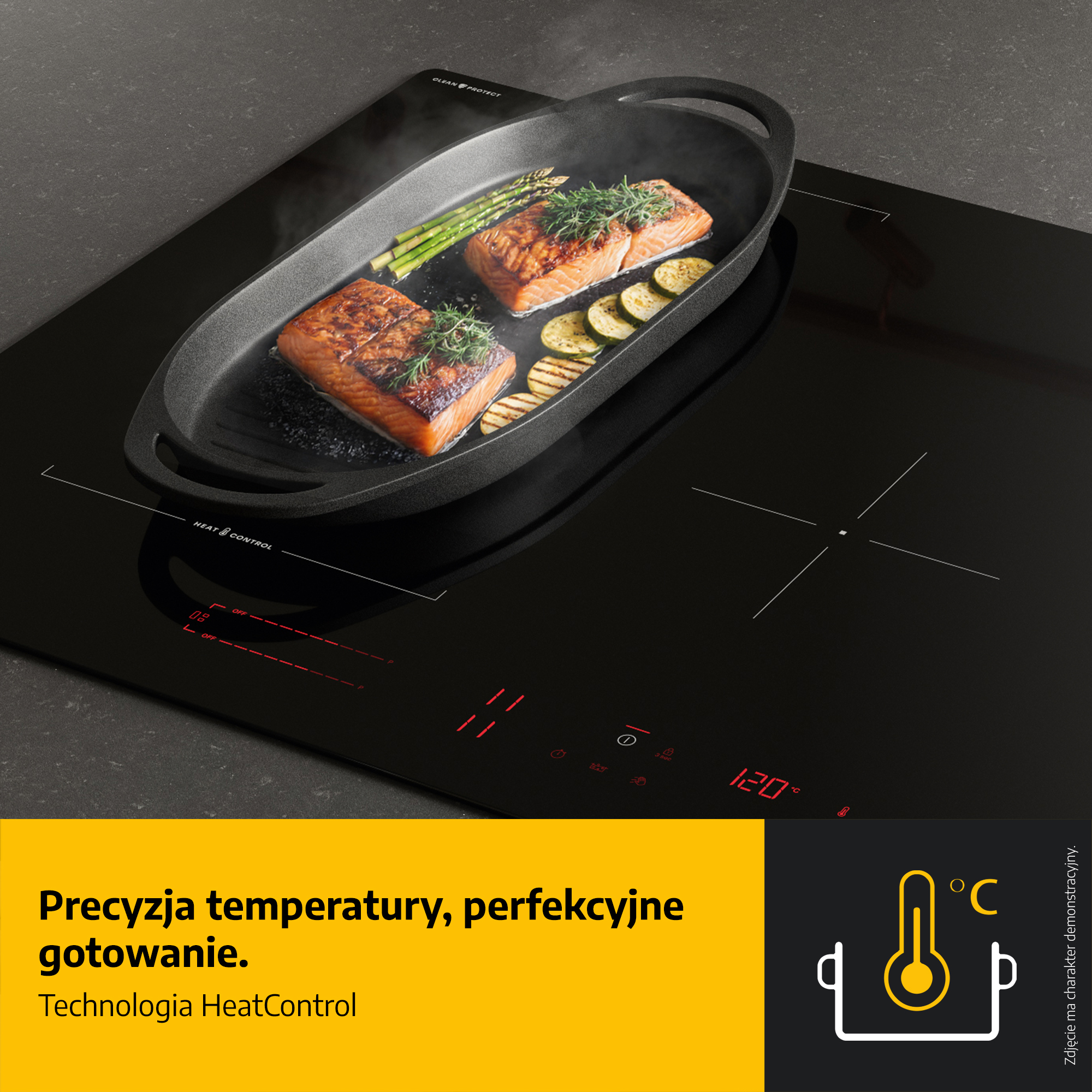 Czarna płyta indukcyjna z łososiem, szparagami i cukinią na patelni. Temperatura wynosi 120 stopni.