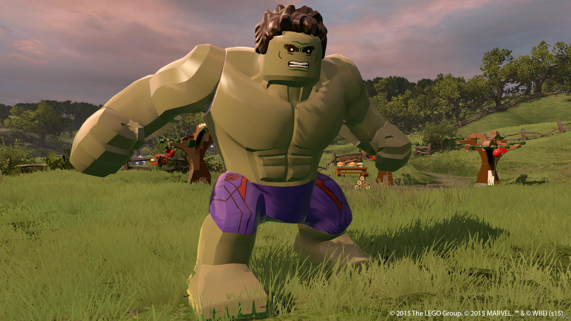 Lego Hulk stoi na polu. Jest zielony z fioletowymi szortami. Drzewa i płot w tle pod zachmurzonym niebem.