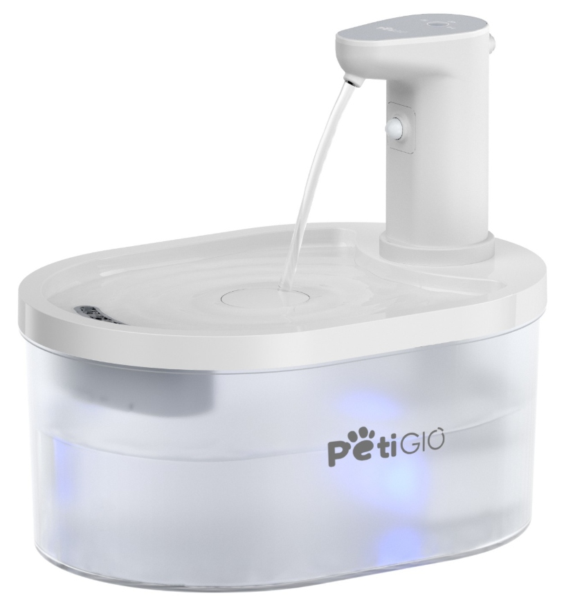 Biała fontanna dla zwierząt domowych. Woda wypływa z dziobka do miski. Podstawa jest przezroczysta z marką 'PetiGio'.