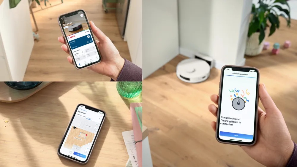 Ręka trzyma telefon z aplikacją smart home. W tle robot odkurzający. Aplikacja pokazuje status sprzątania.