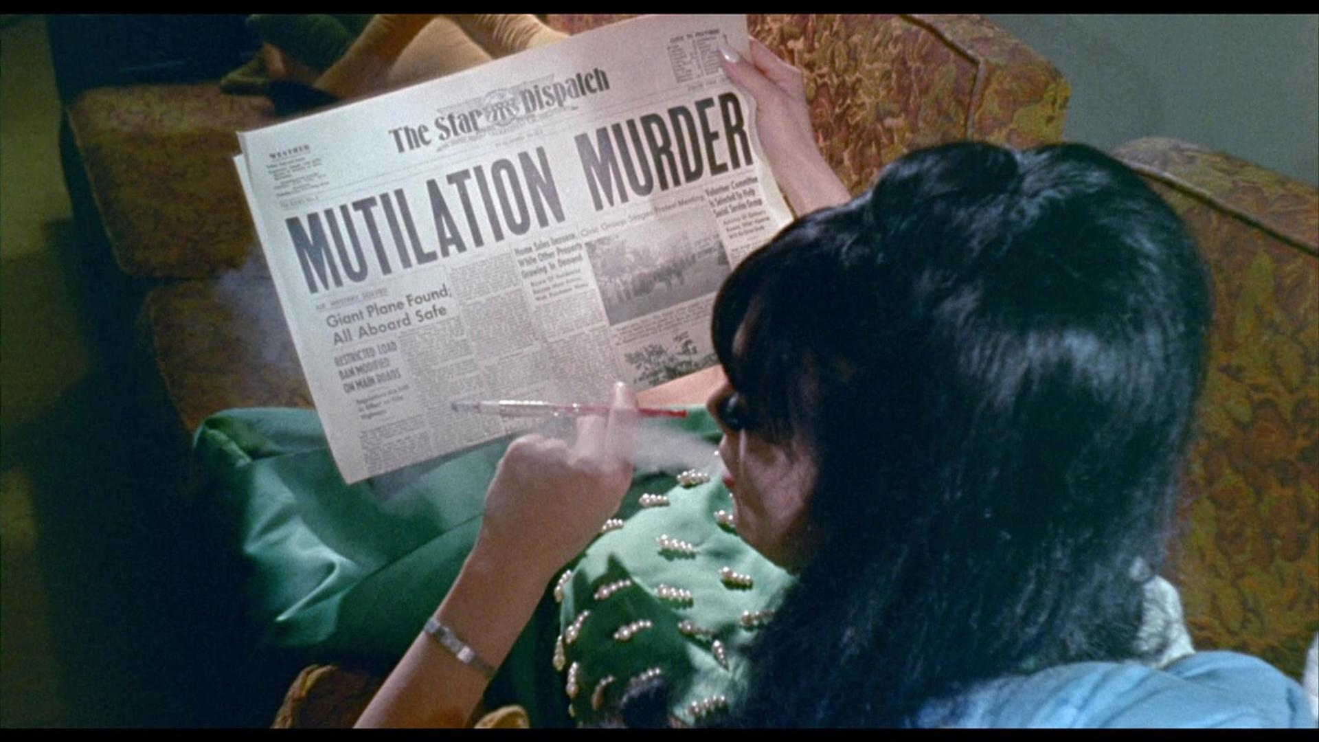 Eine Frau liest eine Zeitung mit der Schlagzeile 'MUTILATION MURDER'. Sie hält eine Zigarette und atmet Rauch aus. Der Hintergrund ist eine Couch.