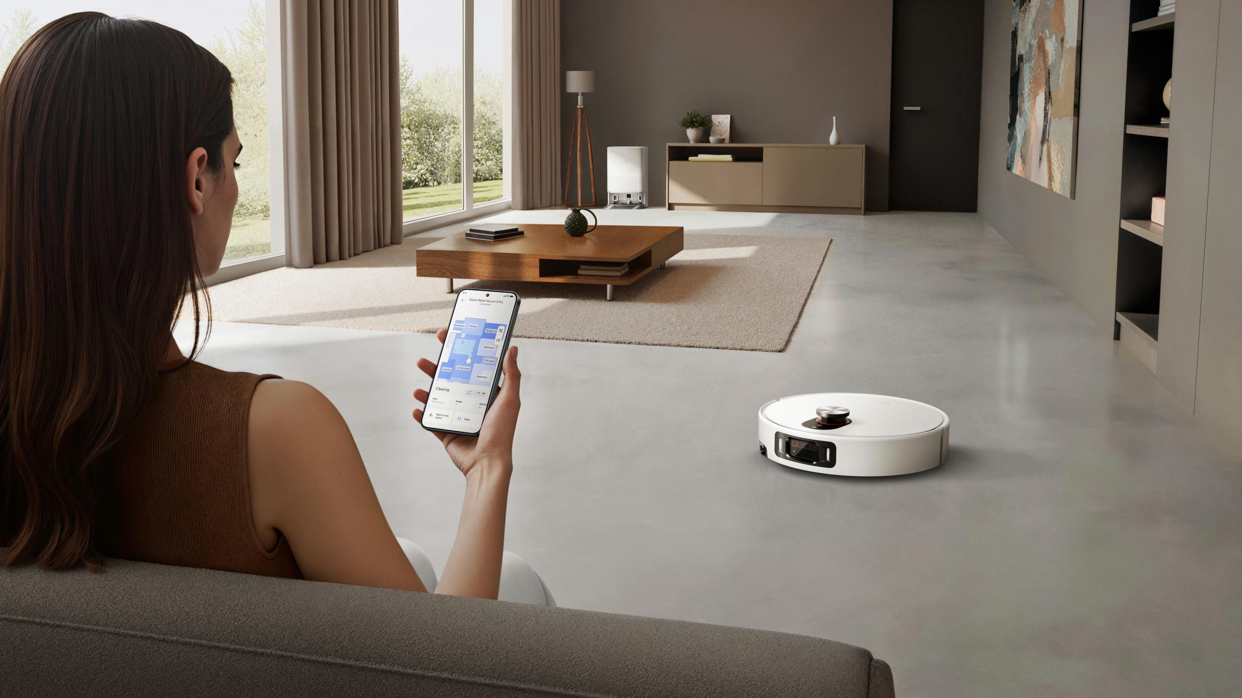 Frau mit Telefon steuert Roboterstaubsauger. Modernes Wohnzimmer. Weißer Staubsauger auf dem Boden.