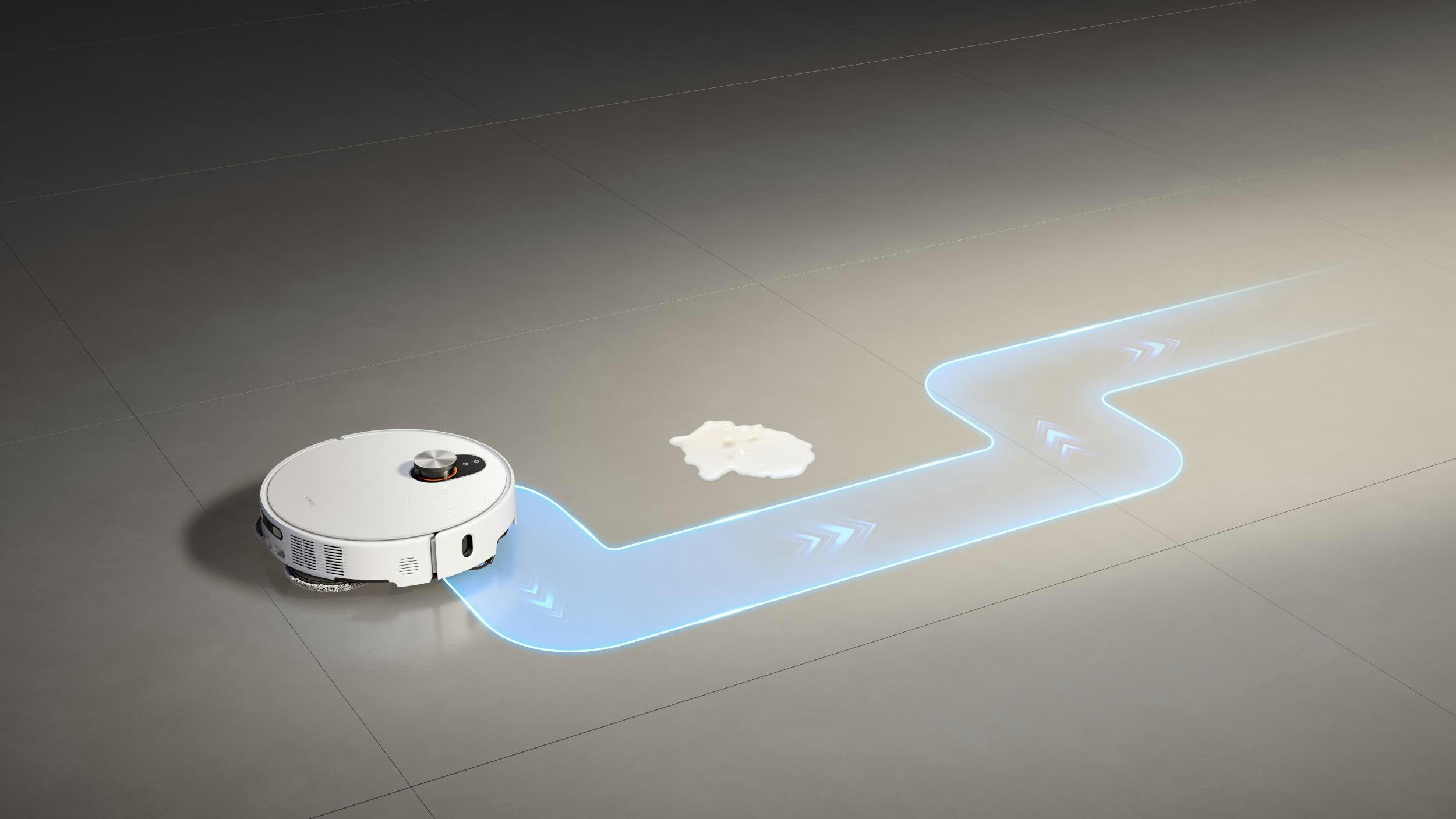 Ein weißer Roboter-Staubsauger auf grau gefliestem Boden. Ein blauer Pfad zeigt seinen Reinigungsweg. Ein weißer Fleck ist ebenfalls sichtbar.