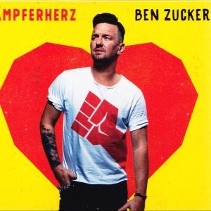 Mann in weißem Hemd mit roter Faust-Grafik steht vor gelbem Hintergrund mit großem roten Herz.