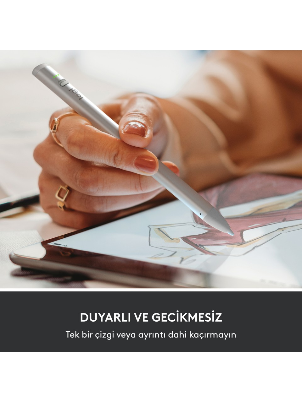 Bir el, bir moda eskizini gösteren bir tabletin üzerinde gümüş bir kalem tutuyor. Elde yüzükler var ve tırnaklar boyalı. Altta metin.