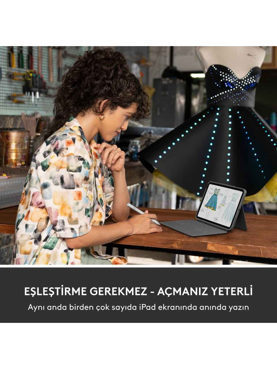 Kıvırcık saçlı bir kadın, tablet üzerinde bir kalem kullanıyor. Arka planda mavi ışıklarla aydınlatılmış siyah bir elbise giymiş bir manken duruyor.