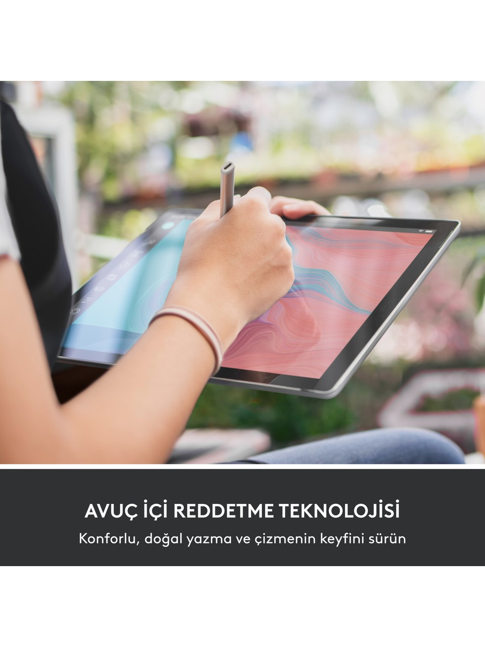 Bir el, bir tabletin üzerinde kalem tutuyor ve çizim yapıyor. Tablet, renkli bir soyut tasarım sergiliyor. Arka plan bulanık bir dış mekan sahnesi.