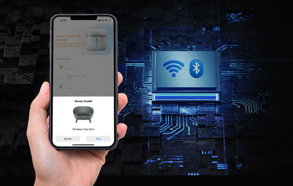 Egy kéz egy okostelefont tart, amelyen a 'Készülék található!' üzenet jelenik meg egy kisállat-kanapéhoz. Bluetooth ikon és kék áramköri háttér.