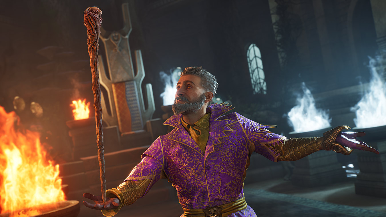 Czarodziej w fioletowej i złotej szacie trzyma laskę, otoczony ogniem i w kamiennej komnacie. Patrzy w górę.