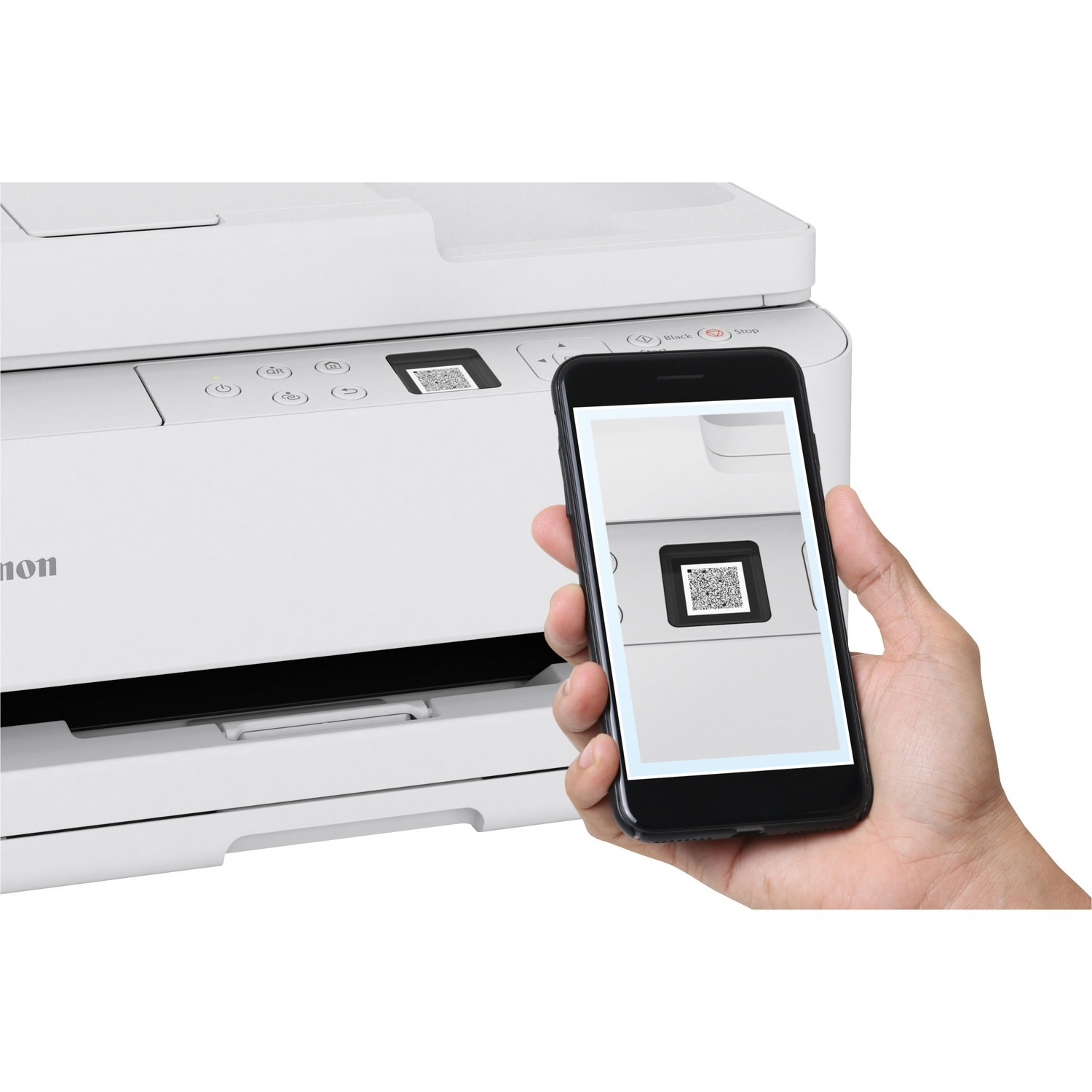 A hand holds a smartphone displaying a QR code. The phone scans a QR code on a white Canon printer. The background is plain white.