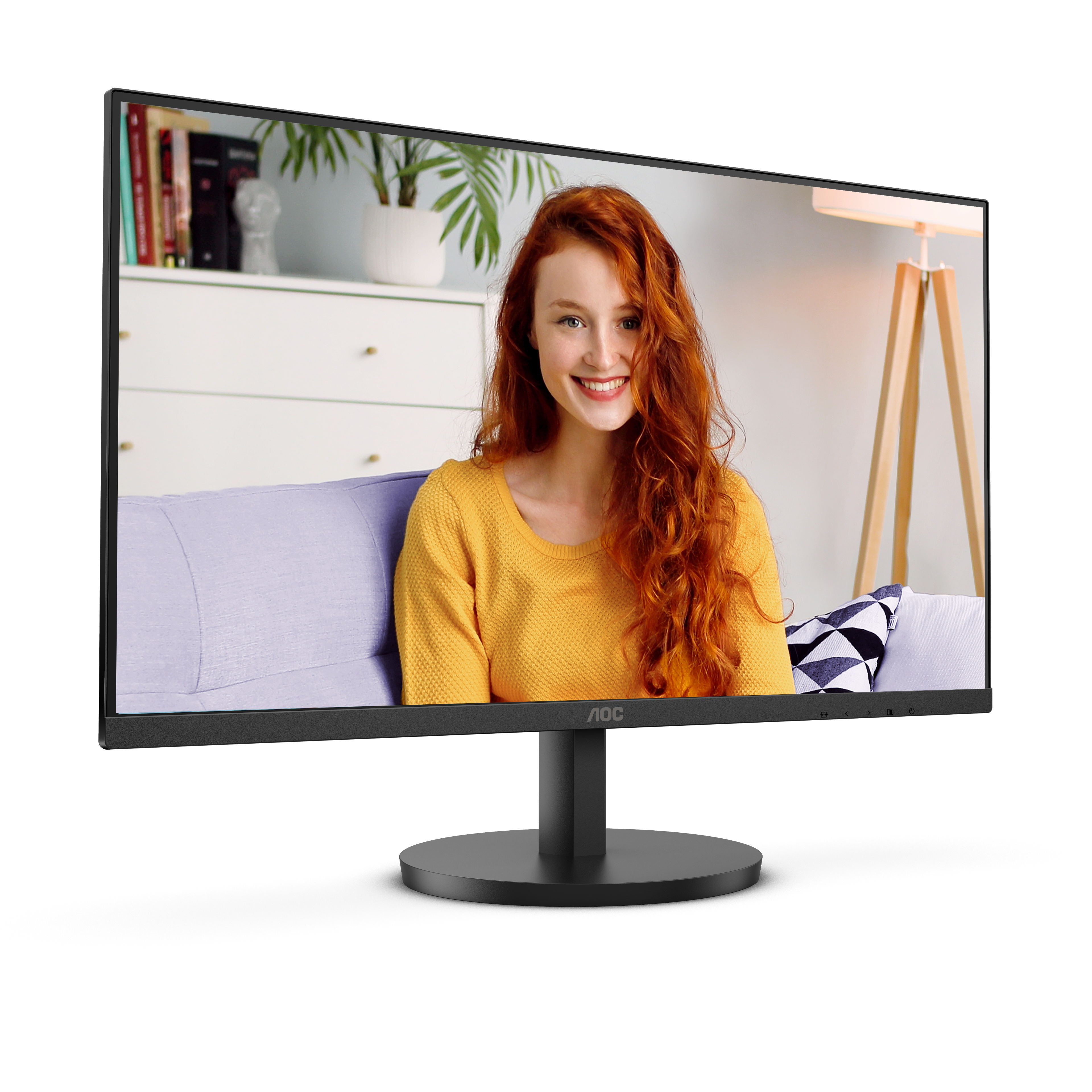 Una donna sorridente con i capelli rossi su un monitor. Indossa un maglione giallo, seduta su un divano viola. Sfondo con pianta e lampada.