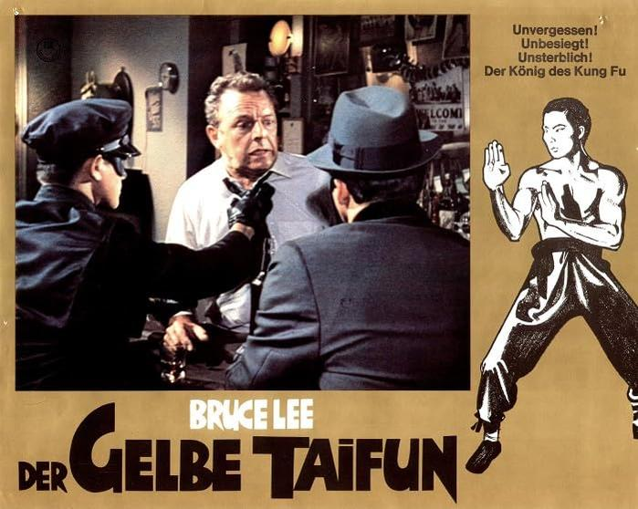 Filmposter mit drei Männern in einer Bar, einer in schwarzer Uniform mit Maske. Bruce Lee in einer Kung-Fu-Pose rechts.