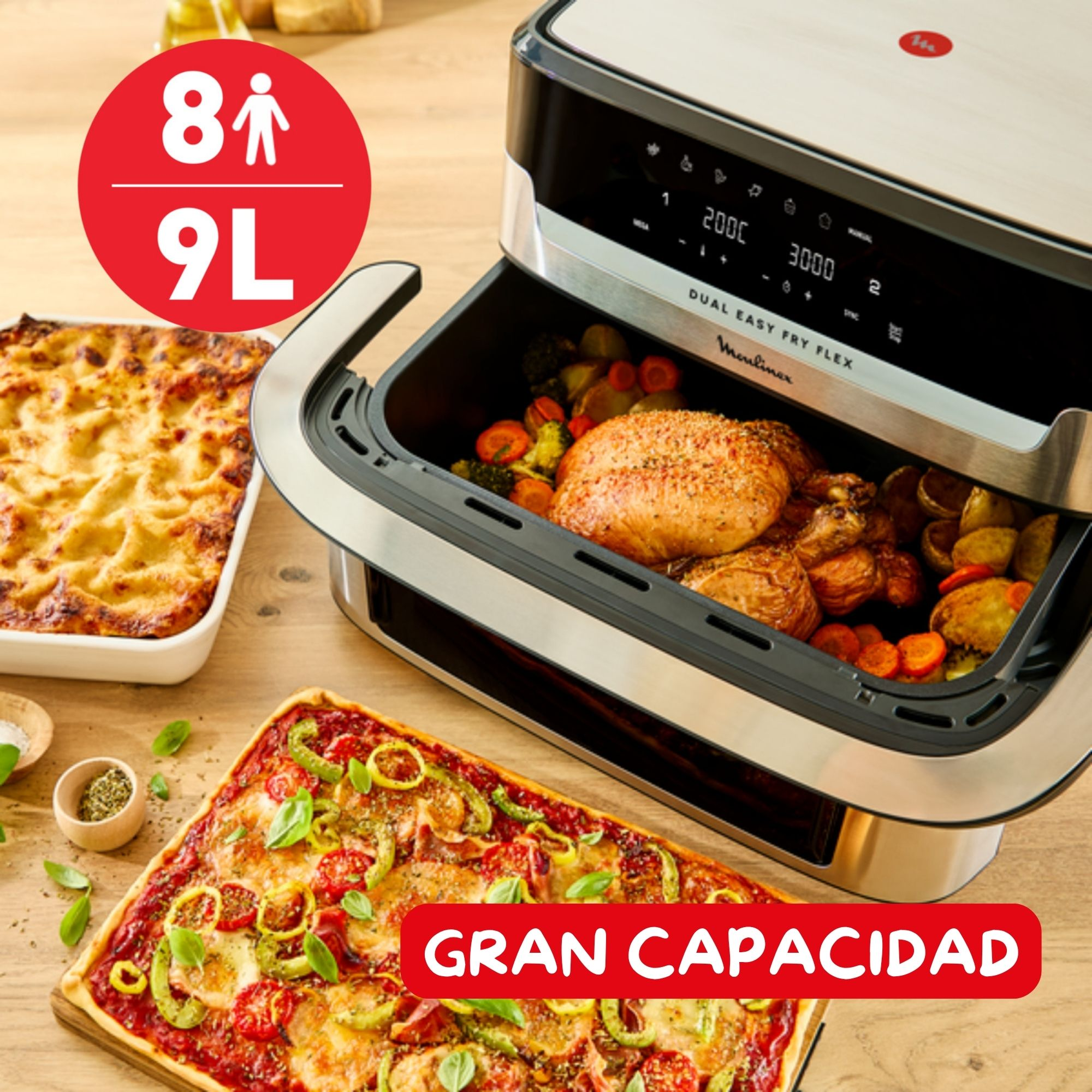 Una freidora de aire con pollo y verduras cocinados. También hay pizza y lasaña. El letrero rojo dice 'Gran Capacidad'.