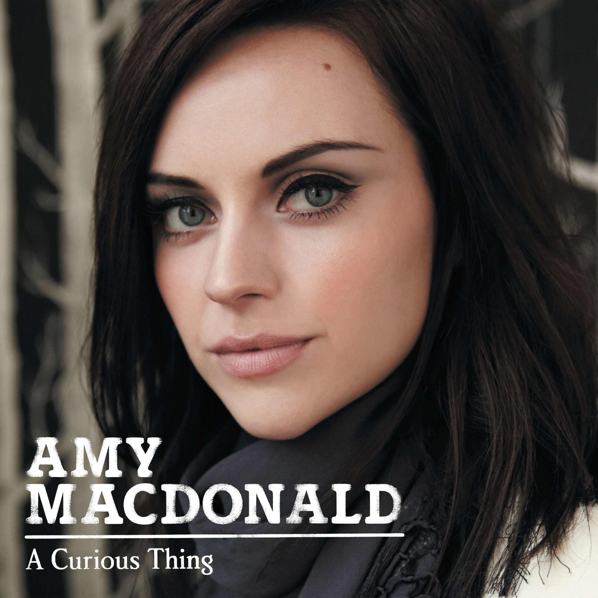 Eine Frau mit dunklen Haaren und heller Haut blickt den Betrachter an. Albumcover mit dem Namen Amy Macdonald.