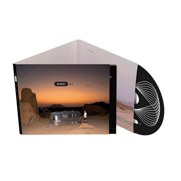 Albumcover. Wüstenlandschaft bei Sonnenuntergang mit silbernem Wohnwagen und einer Person. CD ist schwarz mit weißen Linien.