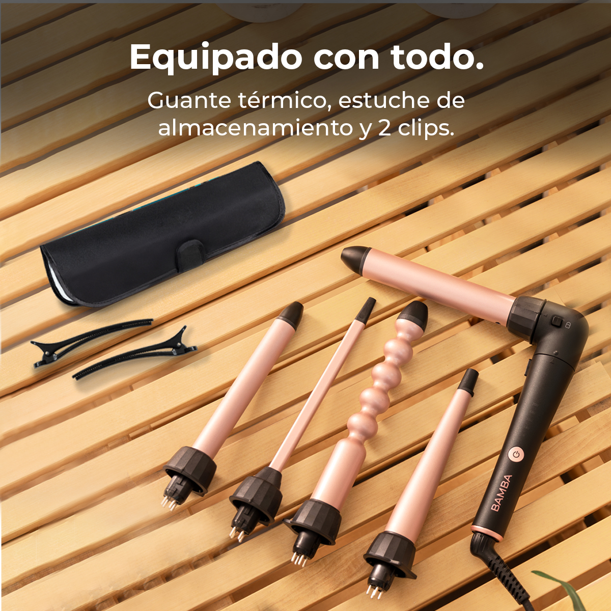 Un juego de rizador de cabello con varios accesorios, una funda negra y clips sobre una superficie de madera. Rizadores rosas y negros visibles.