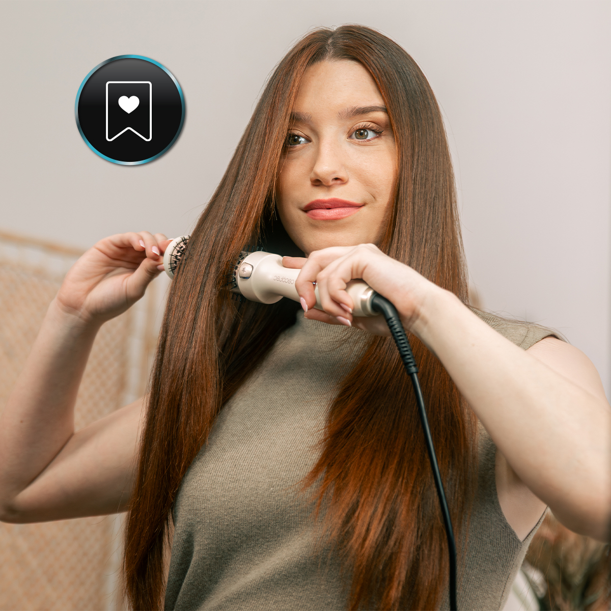 Una mujer usa un moldeador de pelo en su largo cabello castaño. Lleva una camiseta verde. Un icono de marcador está en la esquina superior izquierda.