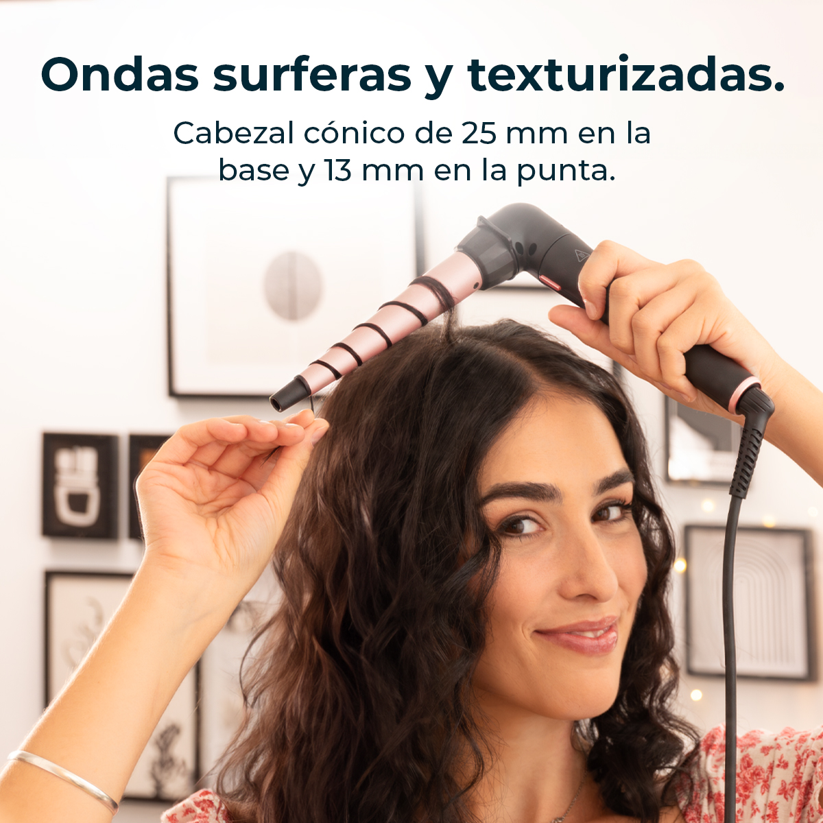 Una mujer se riza el pelo con un rizador. El rizador tiene un barril de oro rosa y un mango negro. Ella sonríe a la cámara.