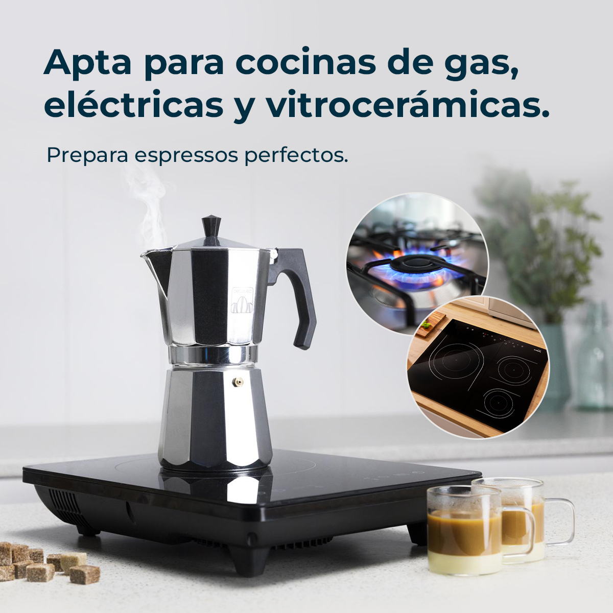 Una cafetera plateada sobre una estufa negra. Dos tazas de café en primer plano. Estufas de gas y eléctricas en el fondo.