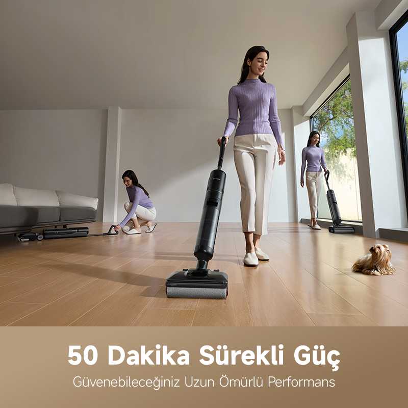 Üç kadın süpürgelerle temizlik yapıyor. Biri ayakta, ikisi eğilmiş. Yakında küçük bir köpek oturuyor. Ahşap zemin, beyaz duvarlar.