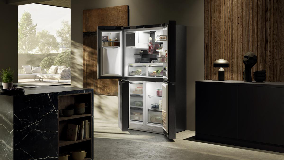 Moderne Küche mit offenem Kühlschrank. Der Kühlschrank ist schwarz, offen und mit Lebensmitteln gefüllt. Blick auf eine Terrasse durch das Fenster.