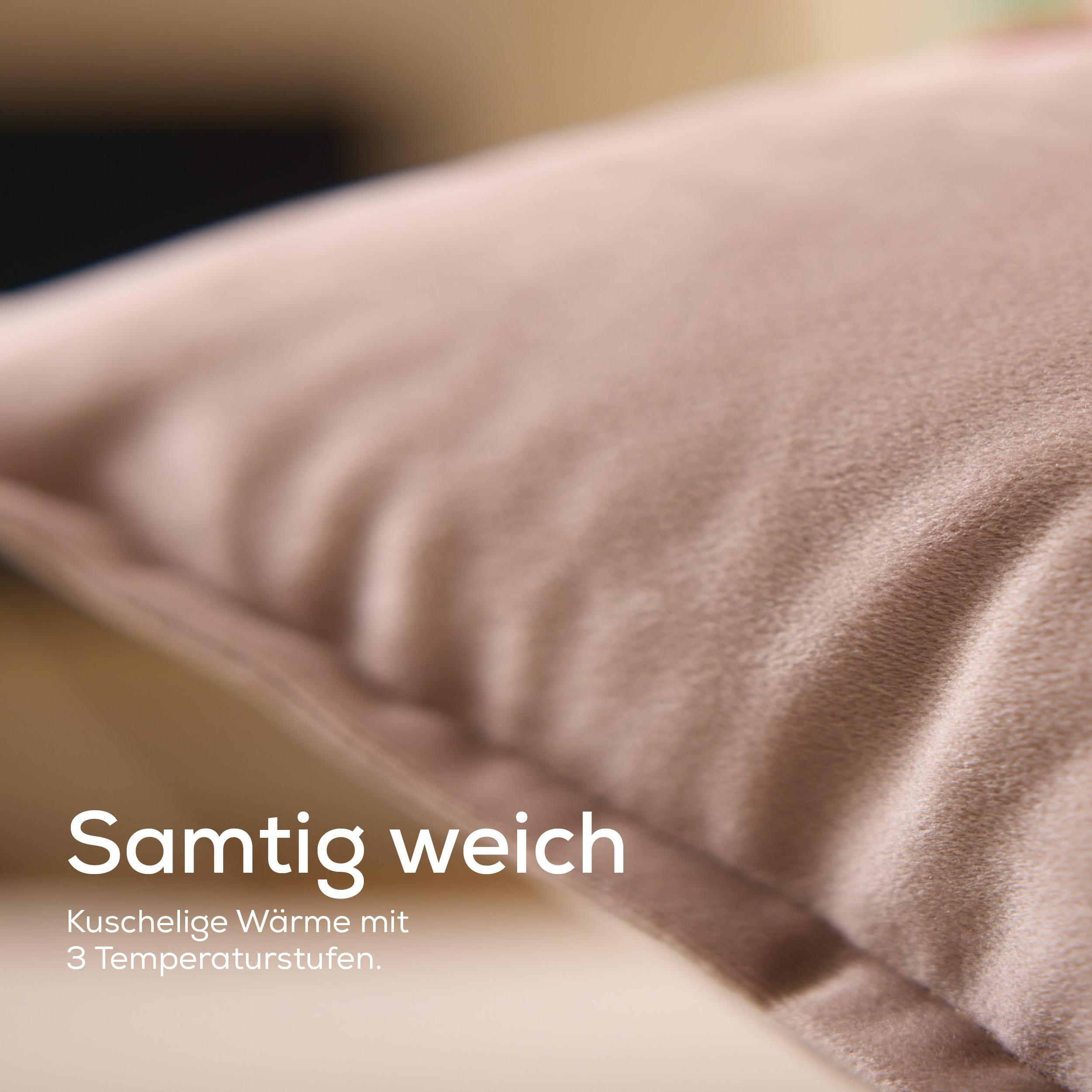 Nahaufnahme eines weichen, beigen Kissens. Text überlagert: 'Samtig weich' und 'Kuschelige Wärme mit 3 Temperaturstufen'.