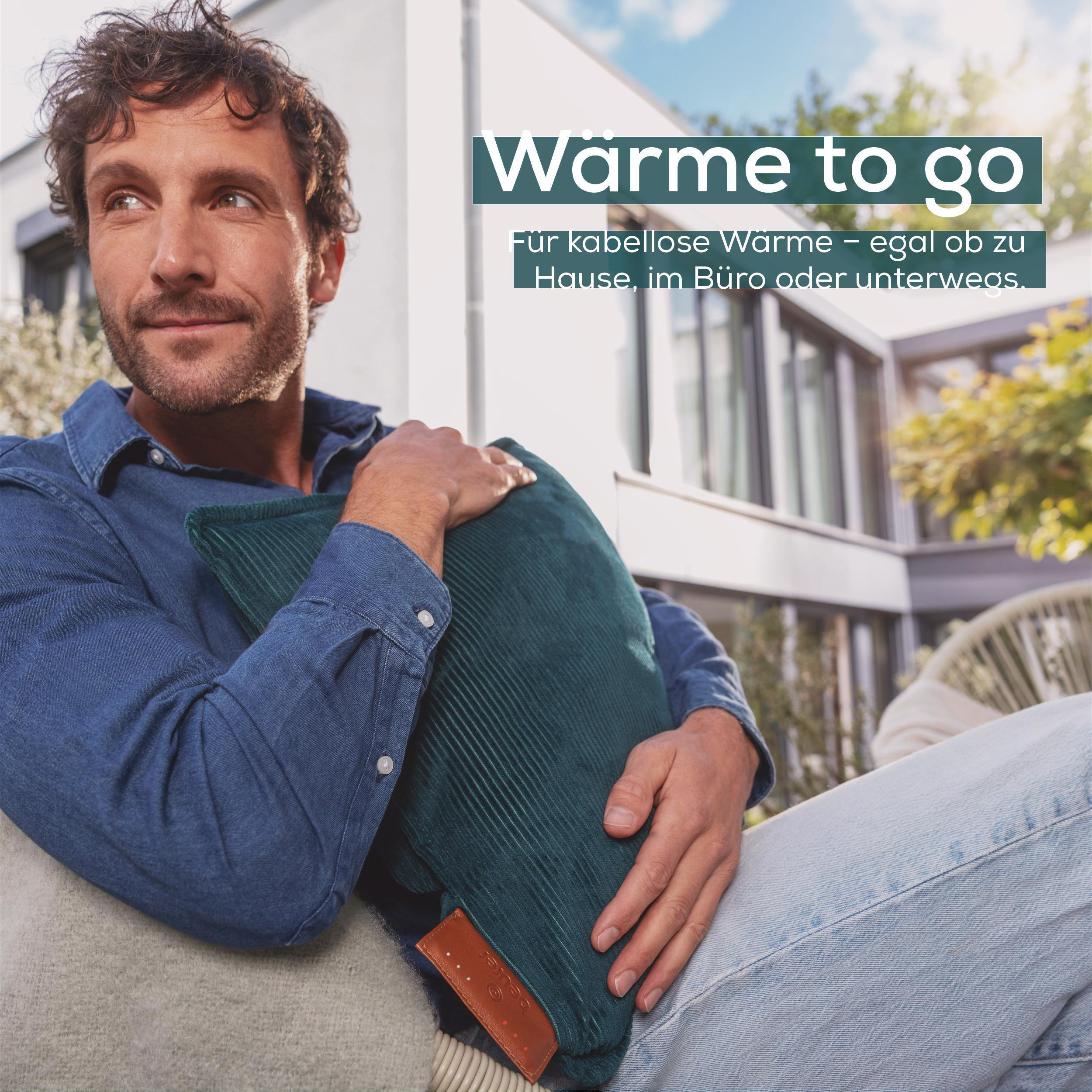 Ein Mann sitzt draußen und hält ein teal-farbenes Kissen. Text sagt 'Wärme to go' und 'Für kabellose Wärme'.