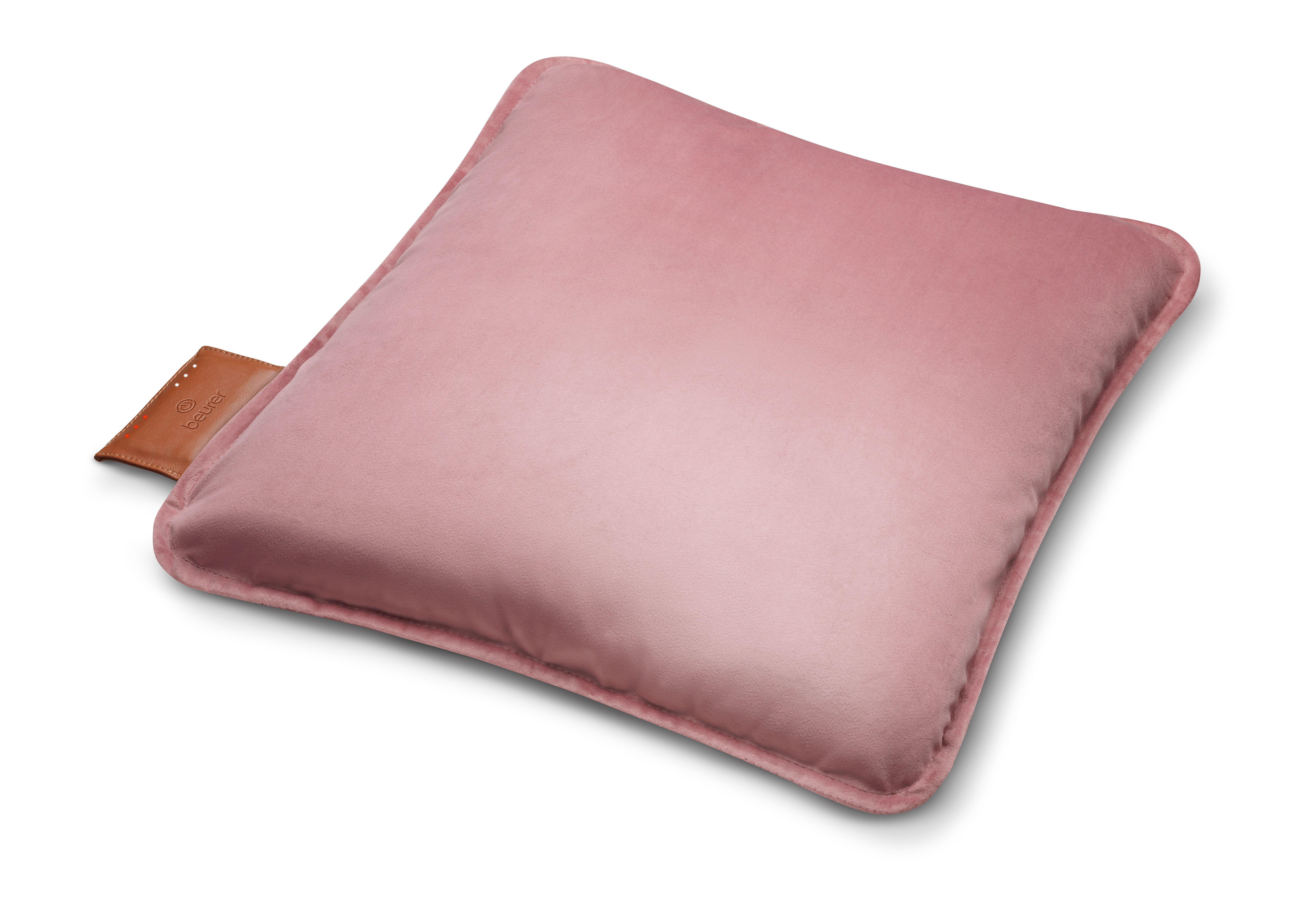 Ein rosa, quadratisches Kissen mit abgerundeten Kanten, das auf einer weißen Oberfläche liegt. Ein braunes Etikett mit 'Beurer'.
