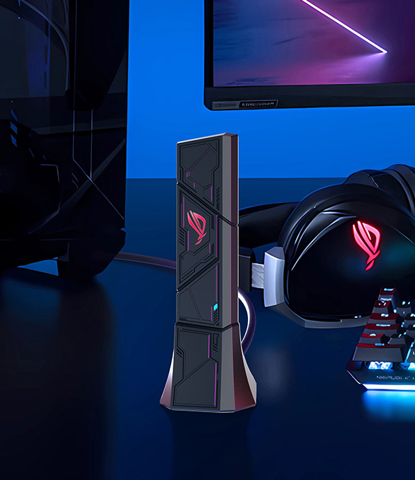 Un'installazione di gioco con un altoparlante nero, cuffie e tastiera. Un monitor mostra un design viola e bianco. Il logo ROG è visibile.