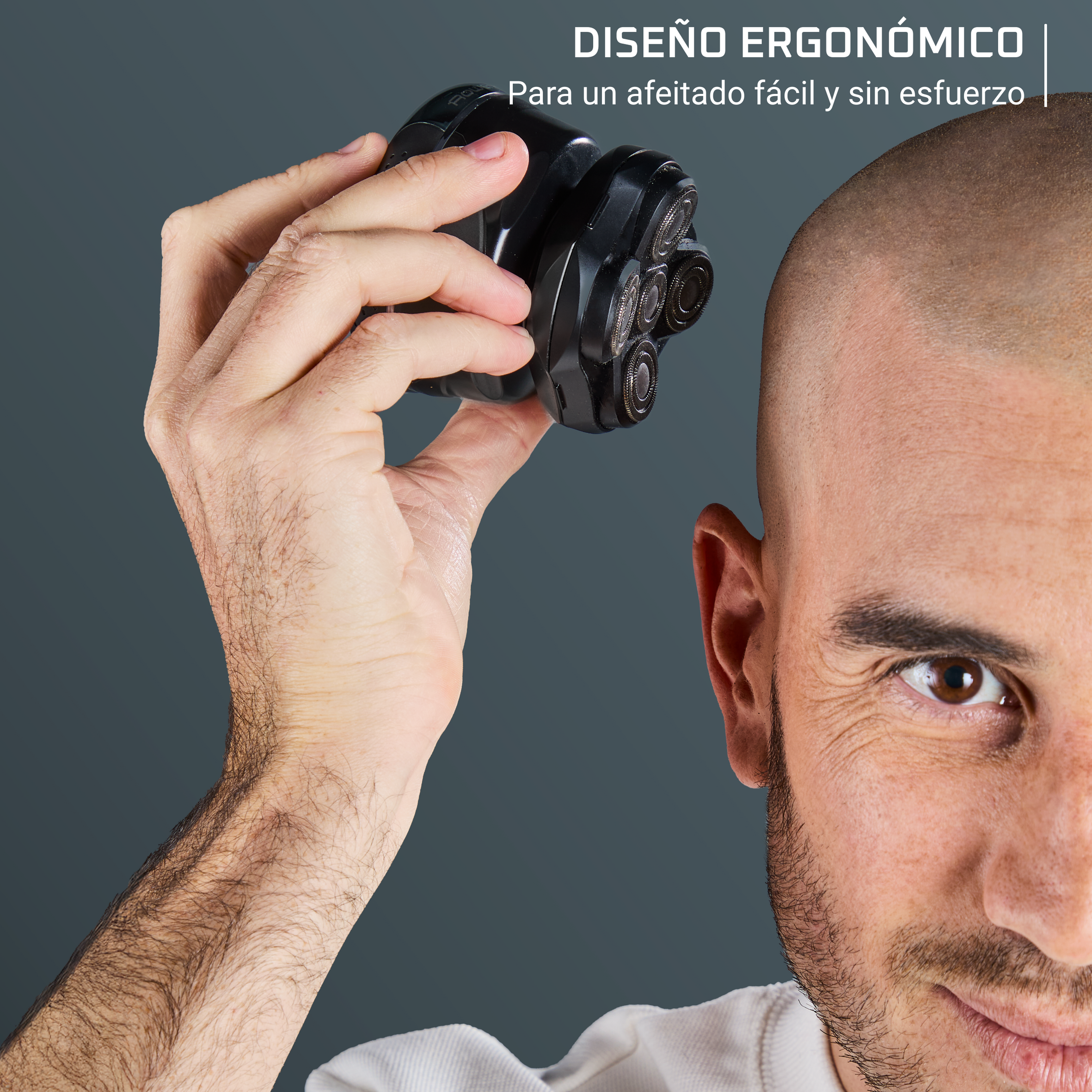Un hombre sostiene una afeitadora negra. Se ven la cabeza calva y la cara. Fondo gris. El texto dice 'Diseño ergonómico para un afeitado fácil'.