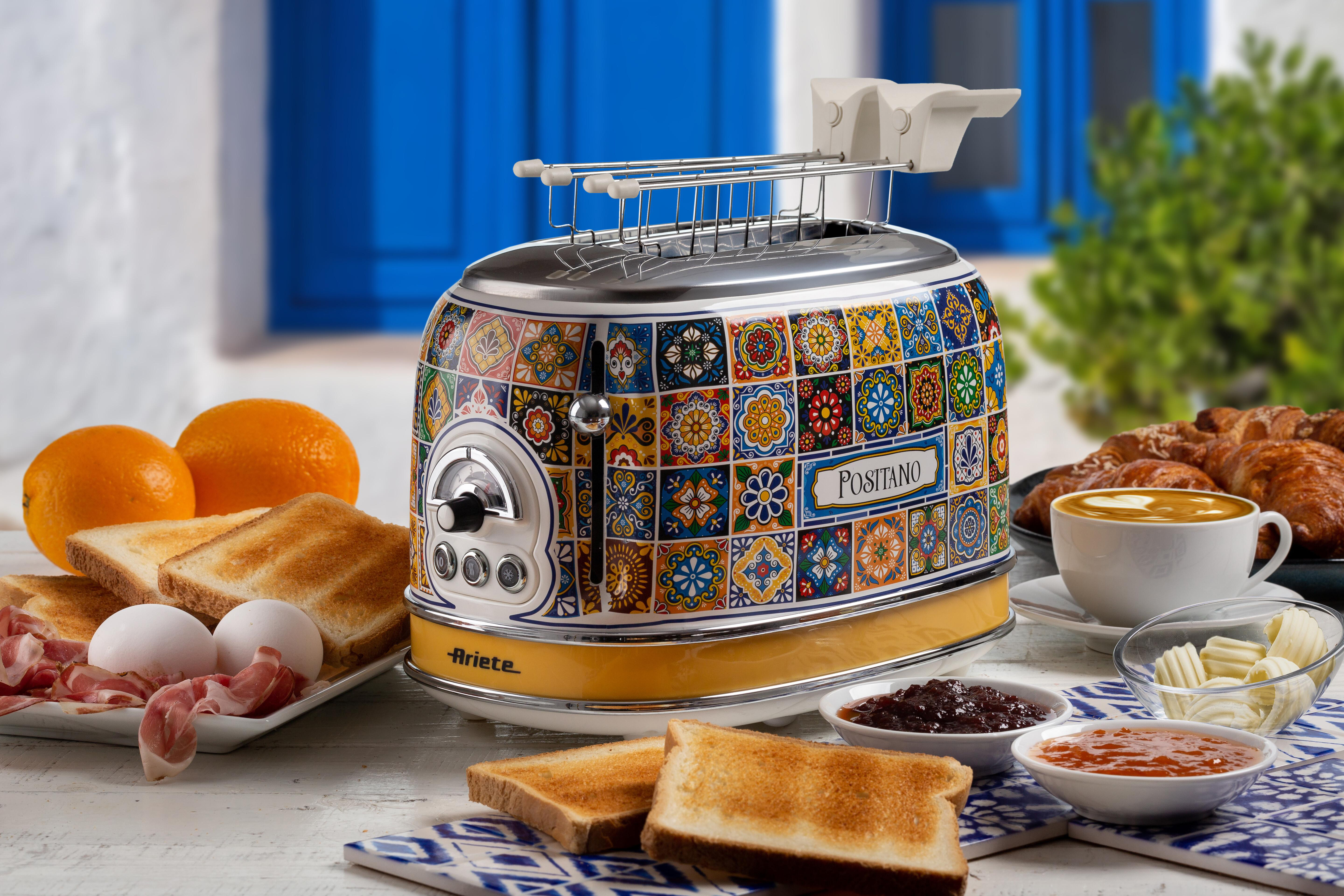 Ein Toaster mit bunten Fliesen, Frühstückszutaten wie Toast, Eier und Orangen. Kaffee, Butter, Marmelade und Croissants sind ebenfalls sichtbar.
