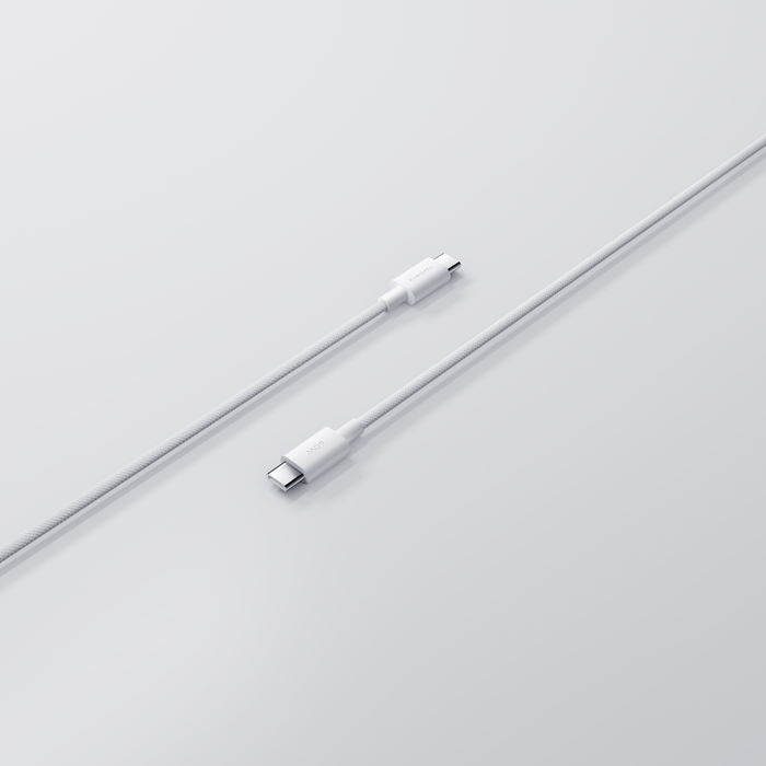 Két fehér USB-C kábel fehér felületen. A kábelek szöget zárnak be, bemutatva a csatlakozókat és a texturált fonást.