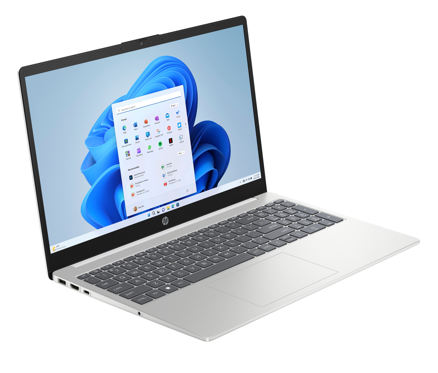Una laptop HP plateada está abierta, mostrando el menú de inicio de Windows 11. El teclado es visible y la pantalla muestra iconos de aplicaciones.