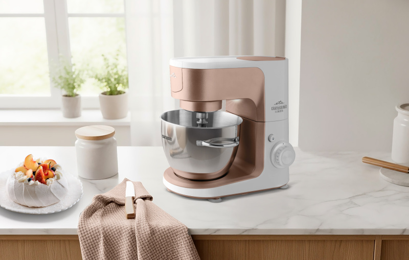 Egy konyhai jelenetben egy mixer, gyümölcsös pavlova és egy üveg látható márványpulton. A háttérben egy ablak látható.