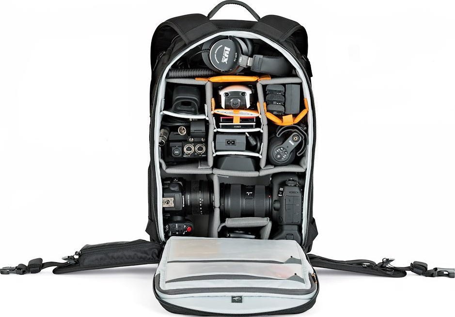 Una borsa nera per fotocamera è aperta, rivelando scomparti pieni di attrezzatura fotografica: obiettivi, un drone, cuffie e altri accessori.