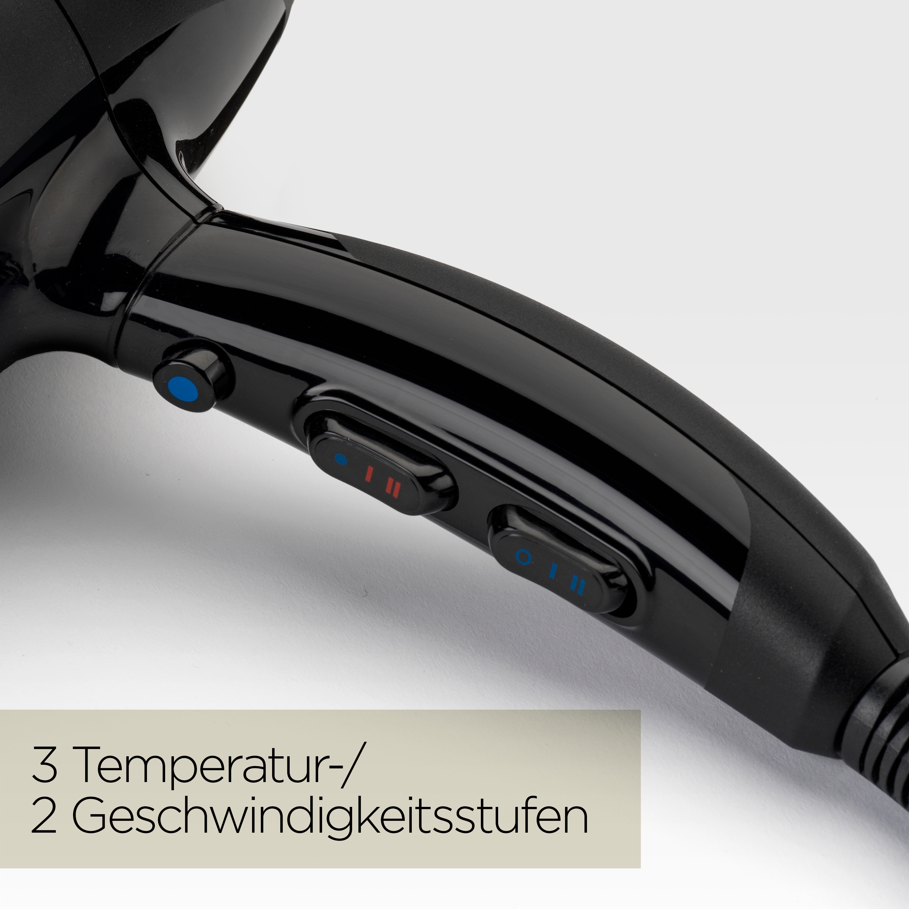 Nahaufnahme eines schwarzen Haartrockners mit Knöpfen und Einstellungen. Text zeigt 3 Temperatur- und 2 Geschwindigkeitsstufen.