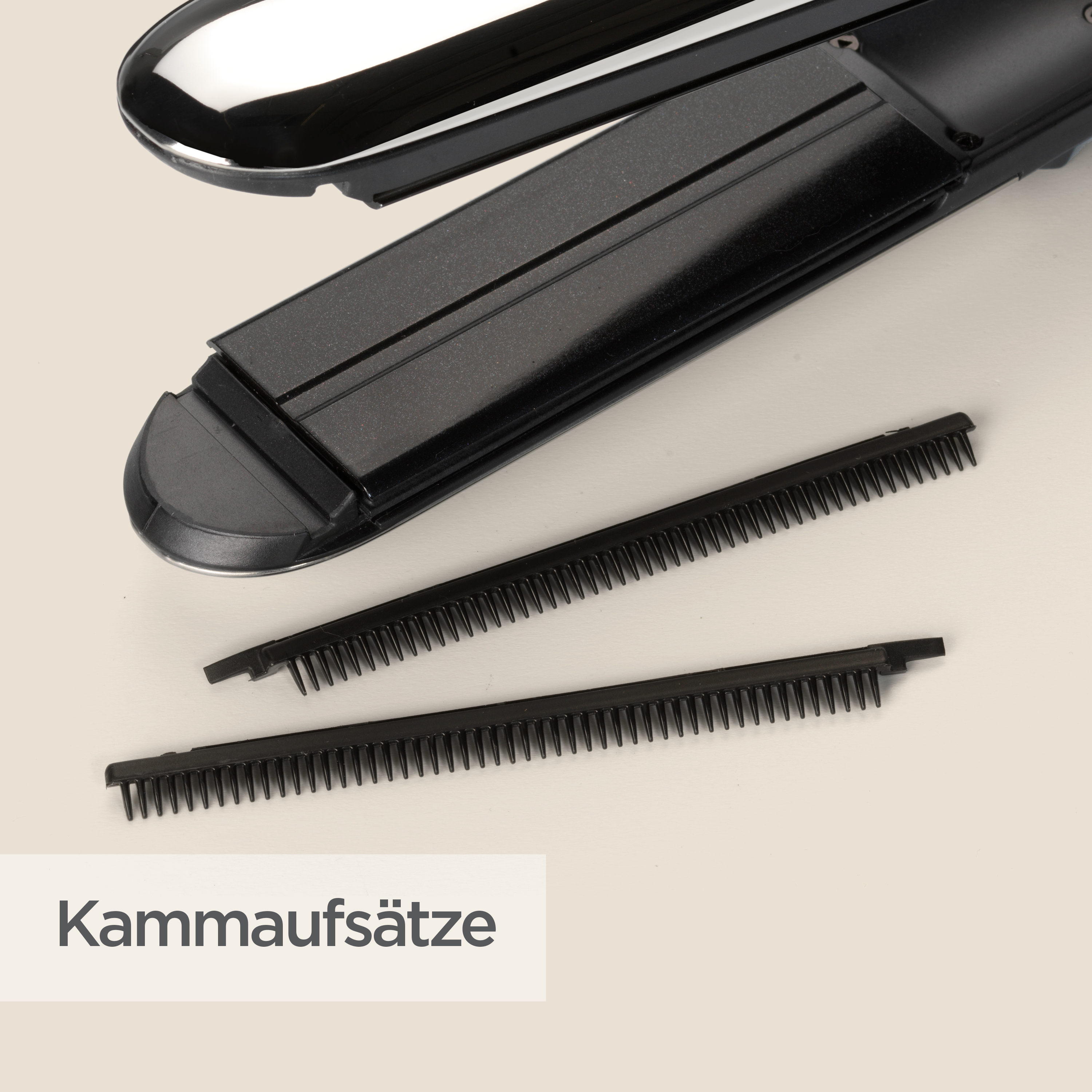 Ein schwarzes Glätteisen mit zwei schwarzen Kammaufsätzen auf einer hellbeige Oberfläche. Das Wort "Kammaufsätze" ist sichtbar.