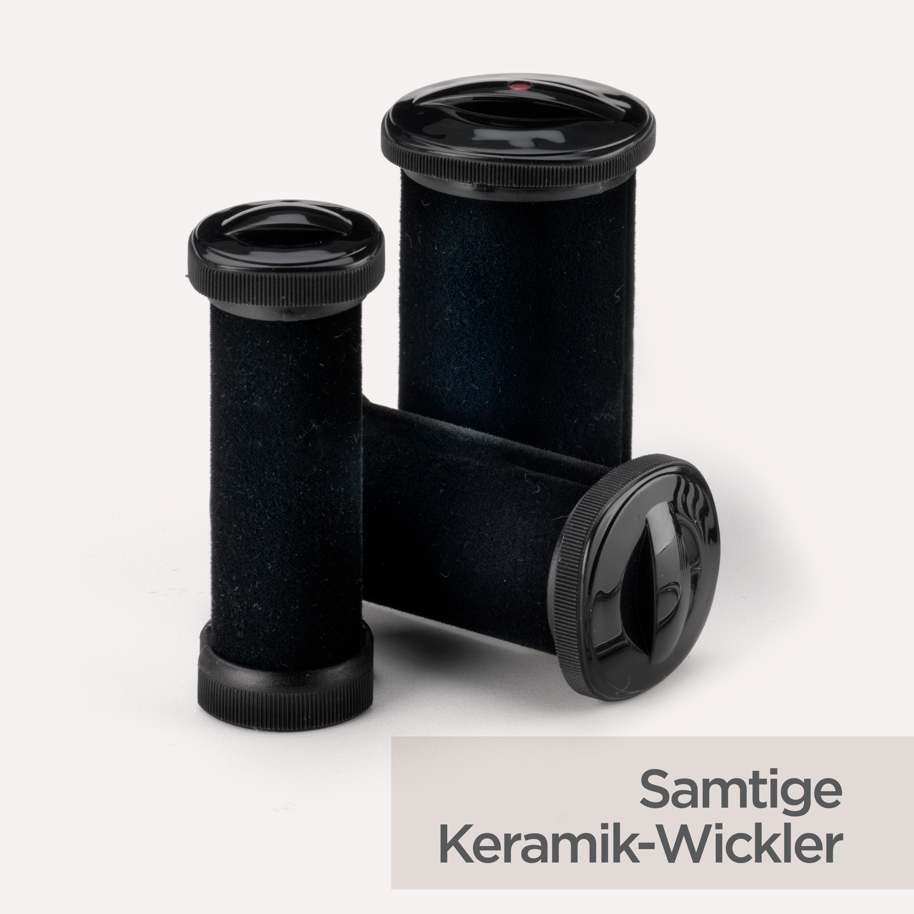 Drei schwarze Haarwickler mit schwarzen Kappen auf weißem Hintergrund. Die Wickler haben eine samtige Textur.
