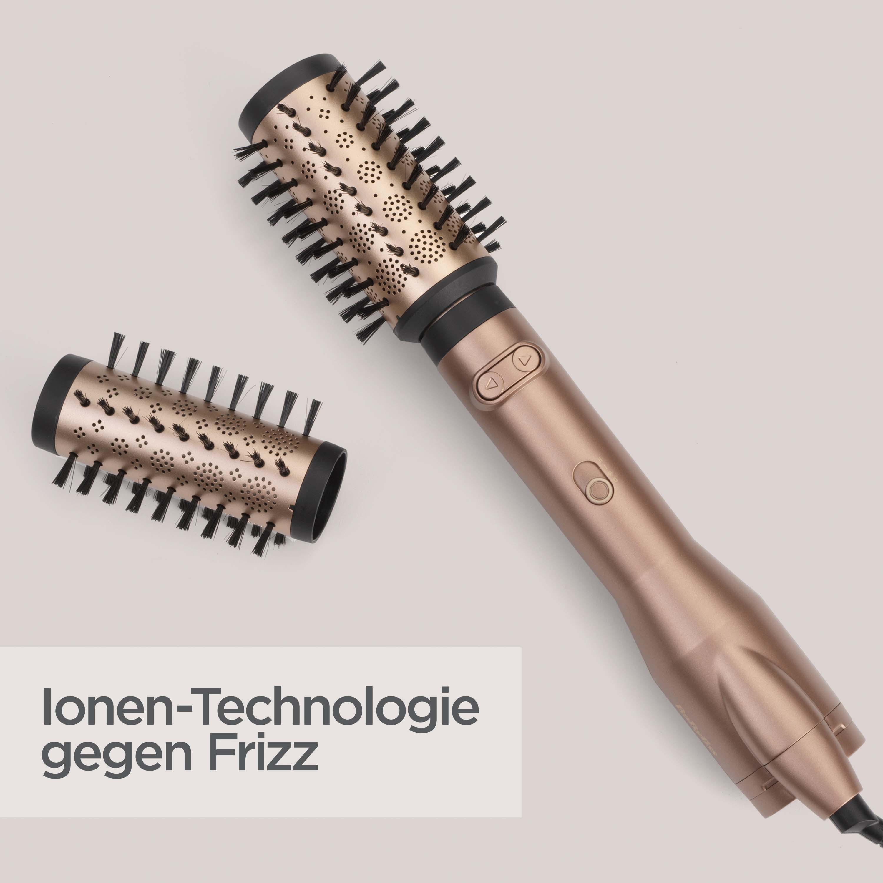 Eine goldene Haarbürste mit abnehmbarem Kopf, schwarzen Borsten und einem Ein-/Ausschalter. Der Hintergrund ist hellgrau.