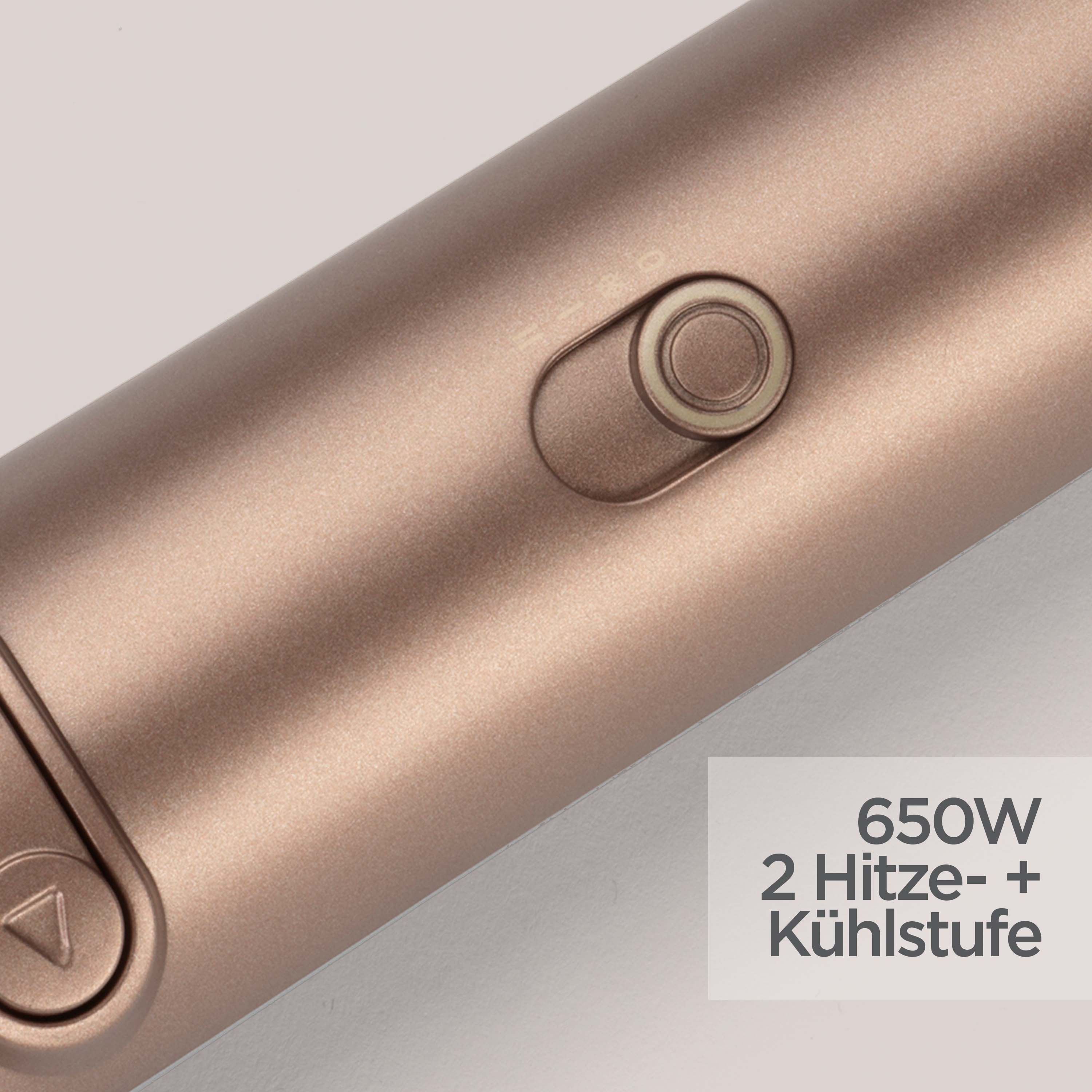 Nahaufnahme eines roségoldenen Haarstyling-Tools mit Knopf und Text: 650W 2 Hitzestufen + Kühlung.