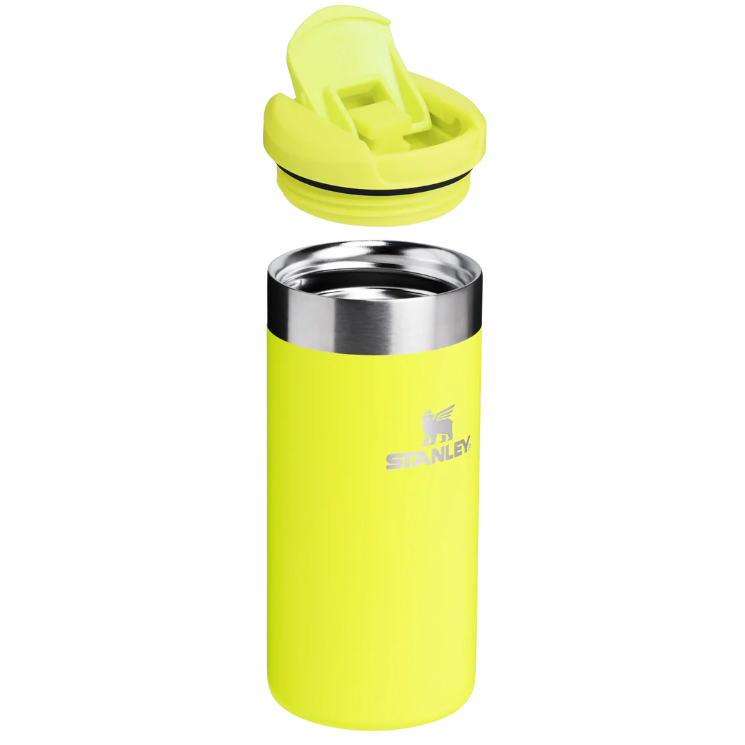 Ayrılmış, eşleşen bir kapağa sahip, neon sarısı bir Stanley bardağı. Gümüş jant ve Stanley logosu mevcut. Kapak ve bardak ayrılmış durumda.